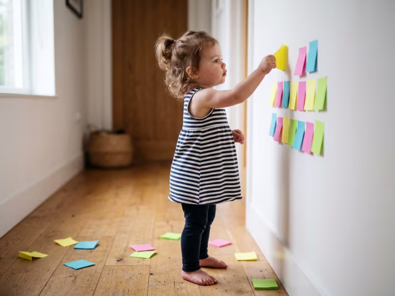 Toddler peeling sticky notes off a wall Toddler peeling sticky notes off a wall